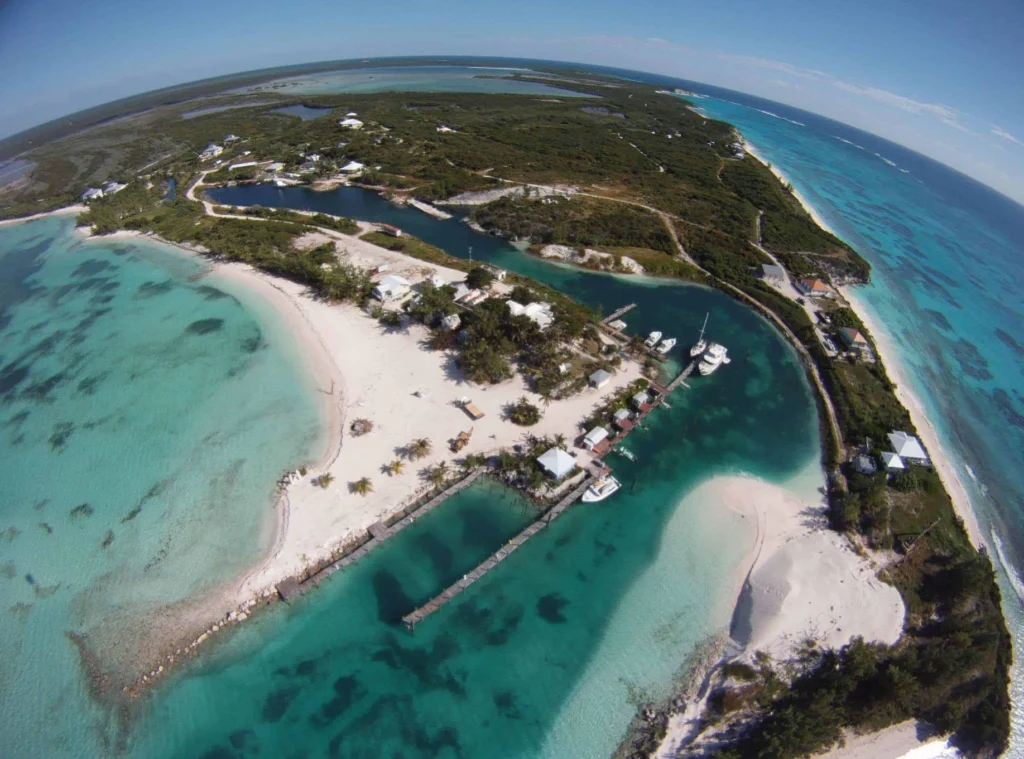 Vista aérea de ilha nas Bahamas cercada por águas azul-turquesa e pequenos píeres.