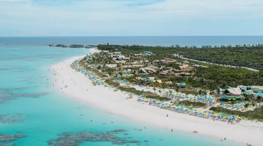 Praia da ilha privada Castaway Cay da Disney com mar azul cristalino, areia branca e estrutura de lazer vista de cima.