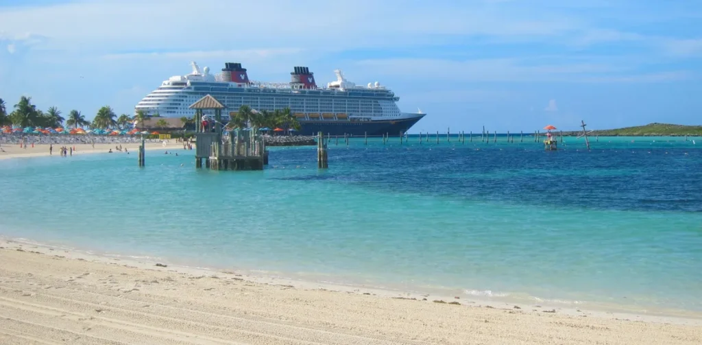 A praia de Castaway Cay oferece águas calmas e rasas ideais para famílias — e a vista do navio ao fundo lembra que você está em uma experiência exclusiva da Disney Cruise Line.