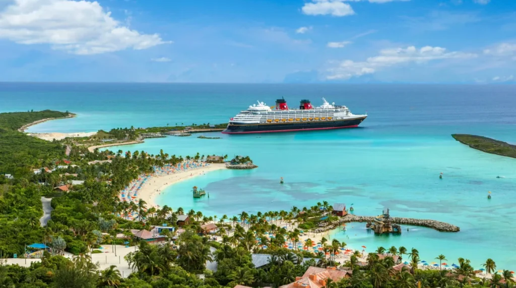 Navio da Disney Cruise Line ancorado em águas cristalinas no Caribe próximo a uma ilha tropical.