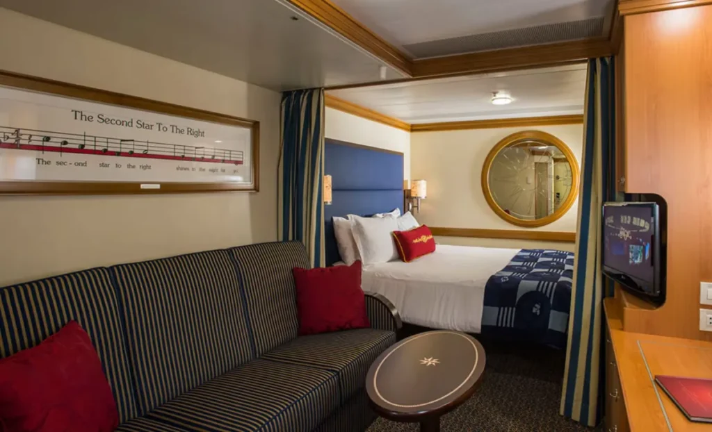 Cabine interna do cruzeiro Disney Fantasy com cama queen, sofá e decoração temática náutica