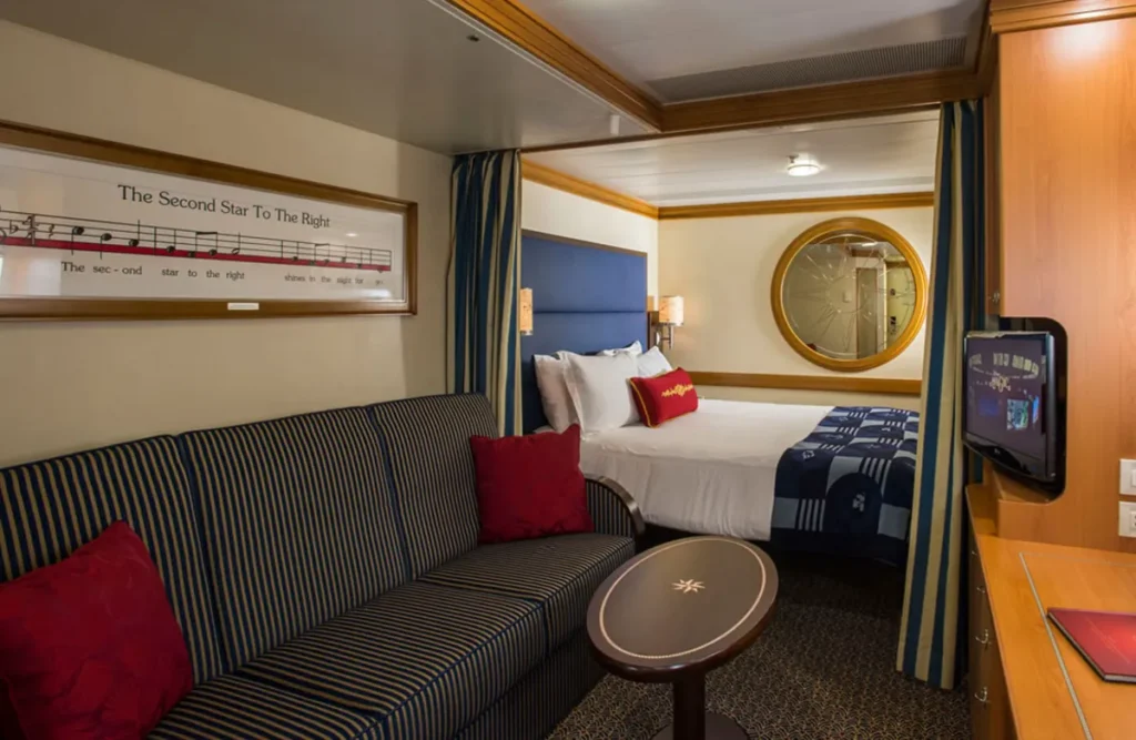 Cabine com janela redonda no Disney Magic mostrando vista para o mar.