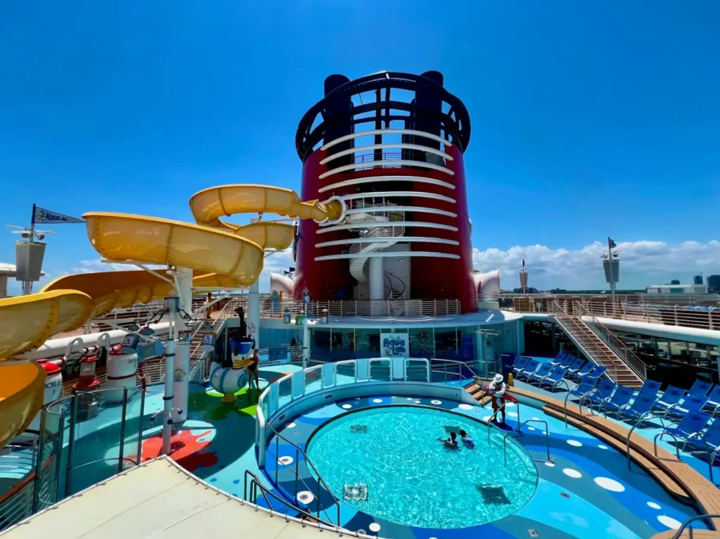 Piscina do Disney Magic com área infantil e toboágua sob céu azul