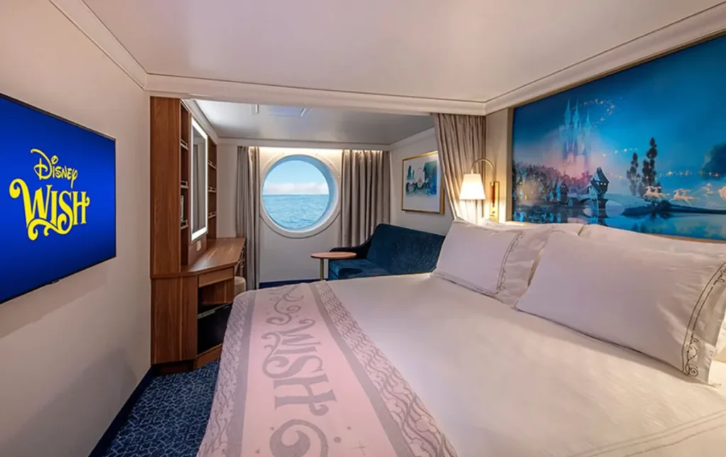 Cabine com janela redonda e vista para o mar no navio Disney Wish.