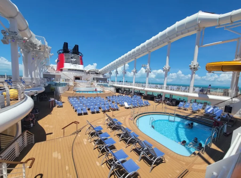 Deck do Disney Wish com piscina, espreguiçadeiras e estrutura do toboágua Aquamouse.
