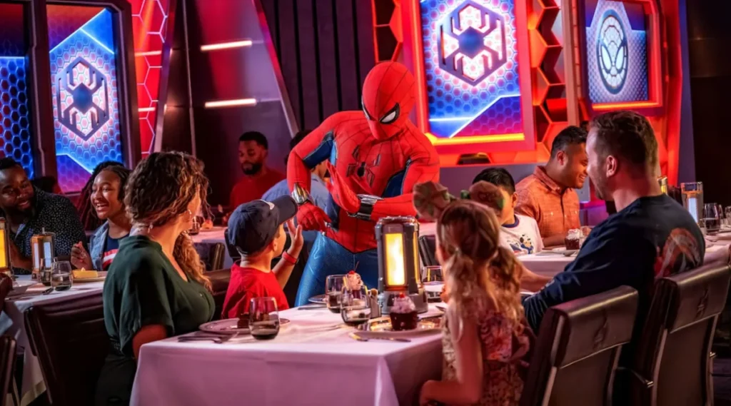 Homem-Aranha interagindo com família em restaurante temático Marvel no Disney Wish.