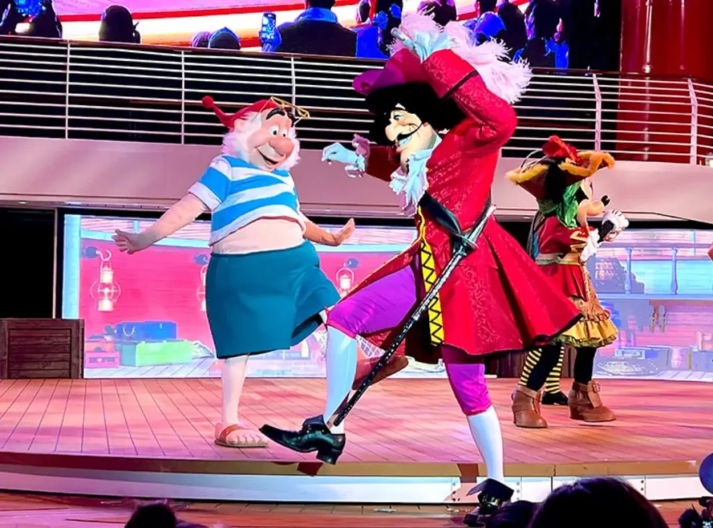 Show temático de piratas no Disney Wish com Capitão Gancho e Sr. Smee dançando no palco.