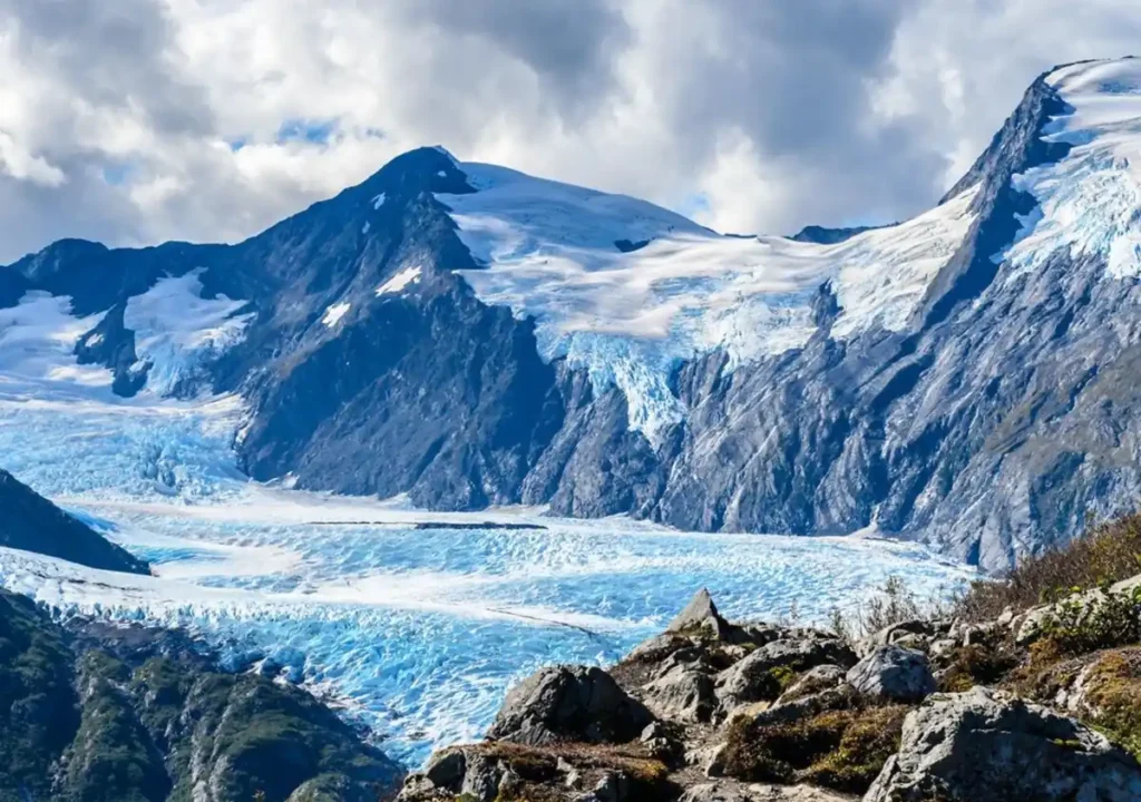 Paisagem glaciar do Alasca com montanhas cobertas de neve e rios de gelo.
