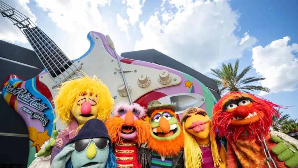 Os Muppets celebram a nova versão da Rock 'n' Roller Coaster em uma divertida foto promocional diante da icônica guitarra gigante da atração.