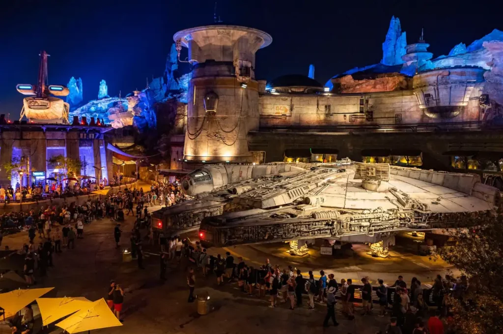 Melhores Atrações Star Wars Hollywood Studios - Vista noturna da Millennium Falcon com iluminação especial em Batuu, no Hollywood Studios.