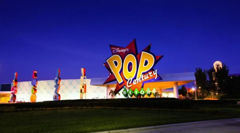 Fachada principal do Disney Pop Century Resort iluminada ao entardecer em Orlando, Flórida.