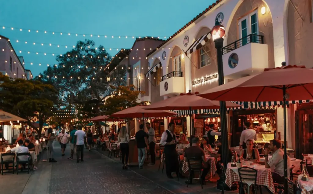 A atmosfera noturna da Española Way, com restaurantes, iluminação acolhedora e mesas ao ar livre.