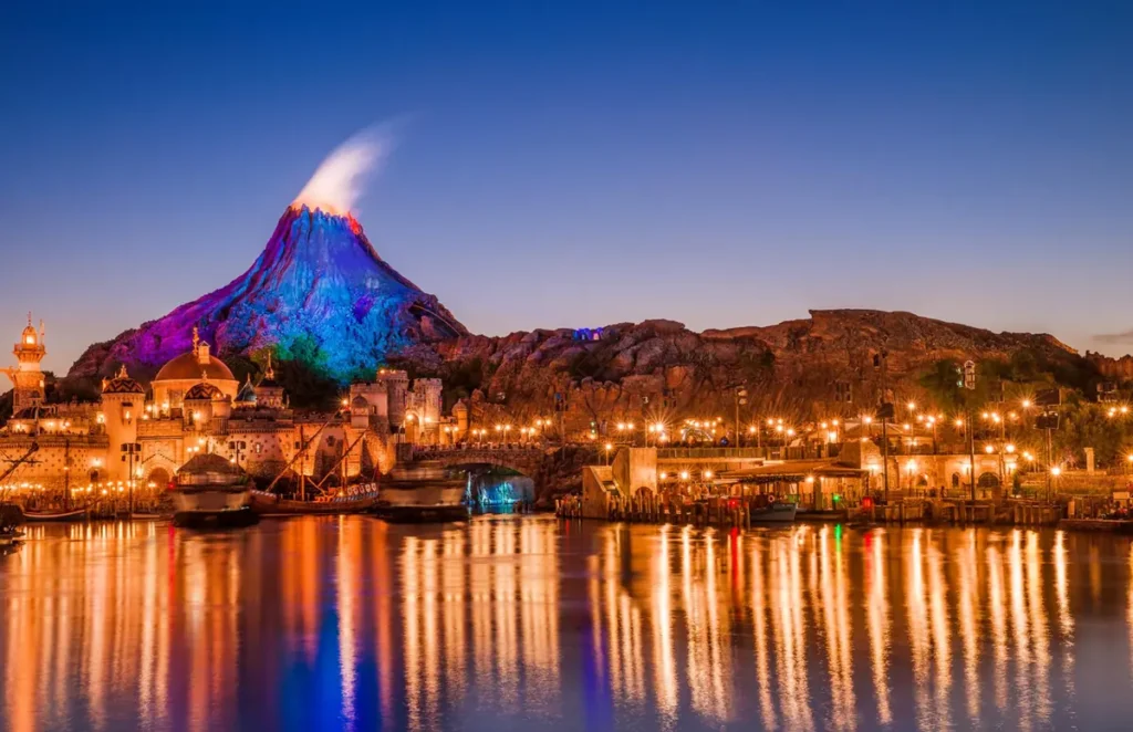 O Monte Prometheus iluminado domina a paisagem da Tokyo DisneySea durante a noite, criando um dos cenários mais icônicos do parque com seus reflexos sobre o Mediterranean Harbor.