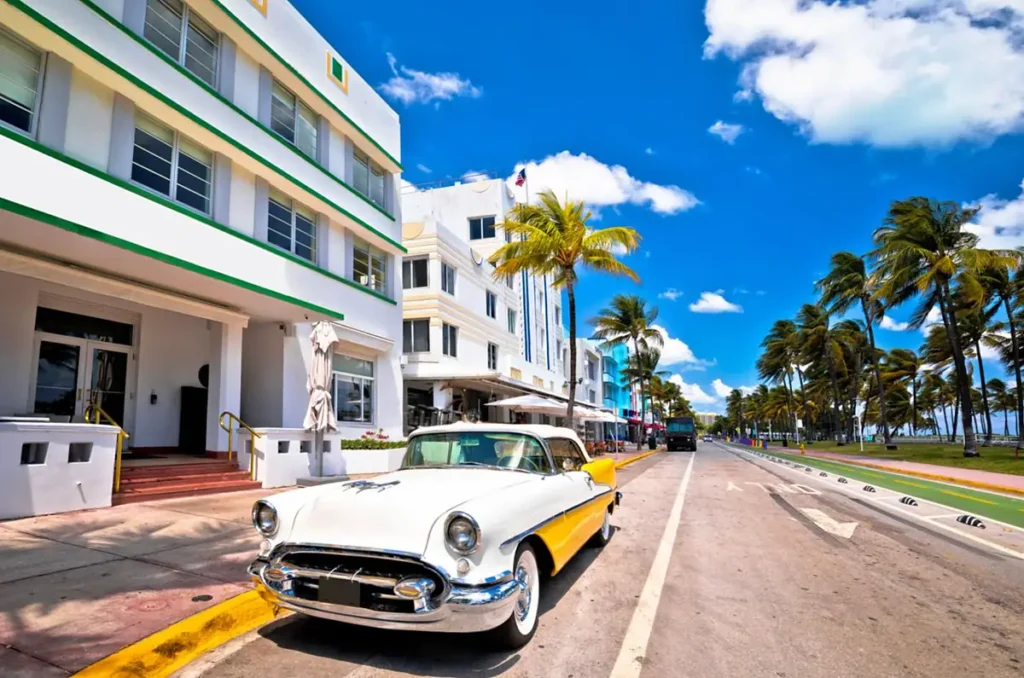 Um automóvel clássico em frente às fachadas Art Déco e às palmeiras da Ocean Drive, em Miami Beach.