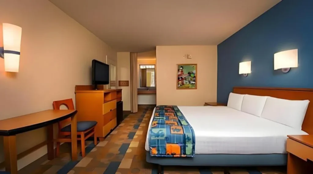 Quarto Standard do Disney Pop Century Resort com cama queen e mesa de apoio.