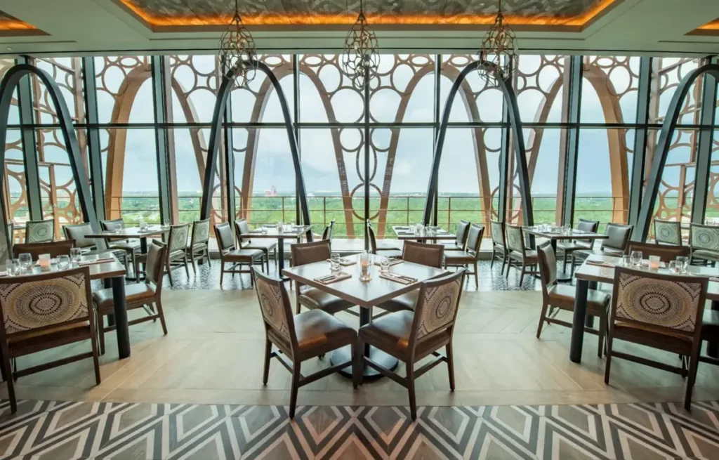 Restaurante do Disney’s Coronado Springs Resort com amplas janelas e vista panorâmica para a área do resort.
