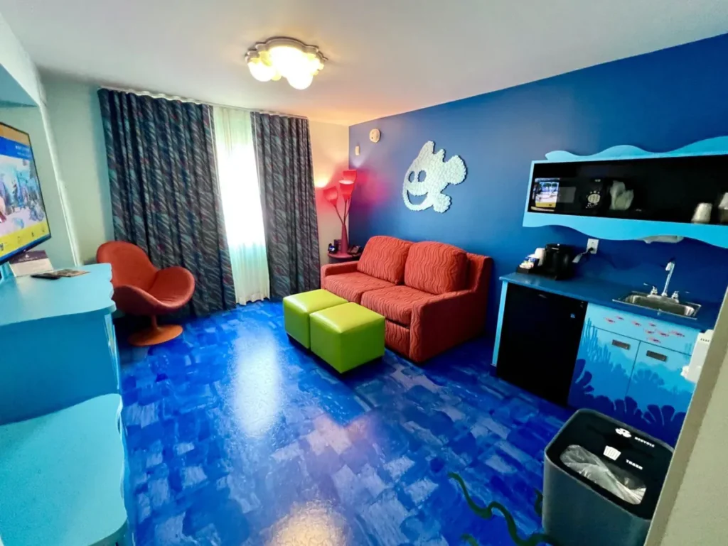 Sala da Finding Nemo Family Suite com sofá, copa e decoração inspirada em Procurando Nemo.
