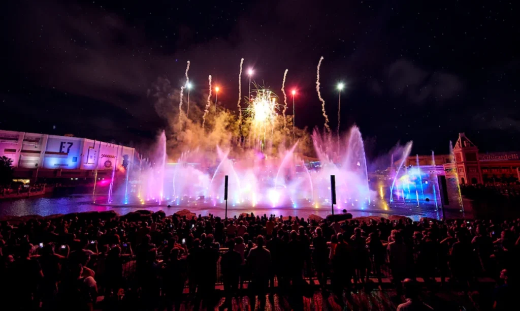 Show de Ano Novo em Orlando com fogos de artifício, fontes iluminadas e público reunido diante de um grande lago.