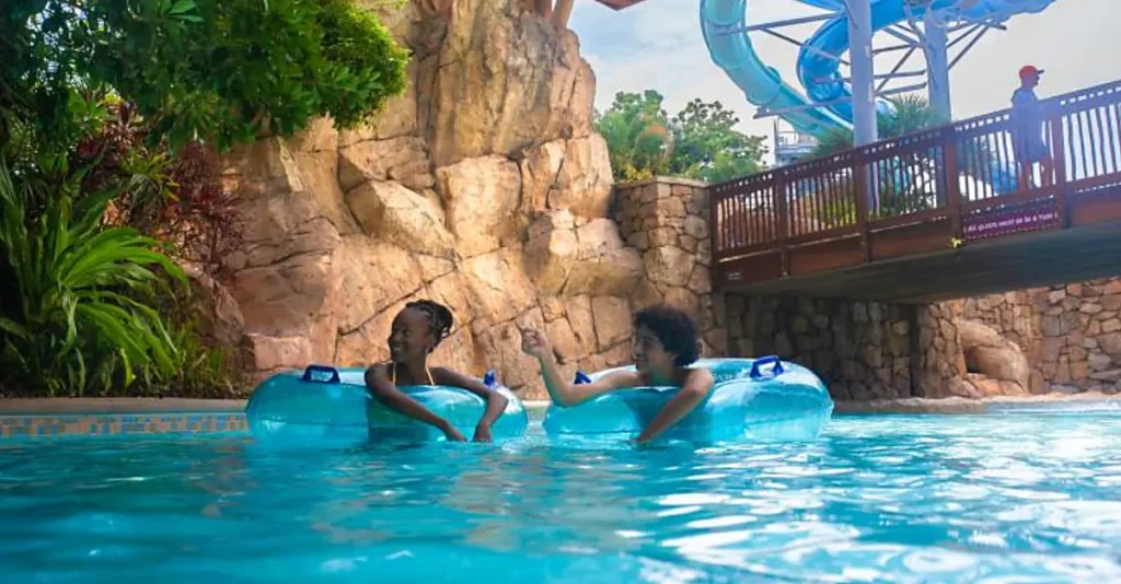 Relaxe nas águas do Aquatica Orlando em um passeio de boia cercado por paisagismo tropical e formações rochosas.