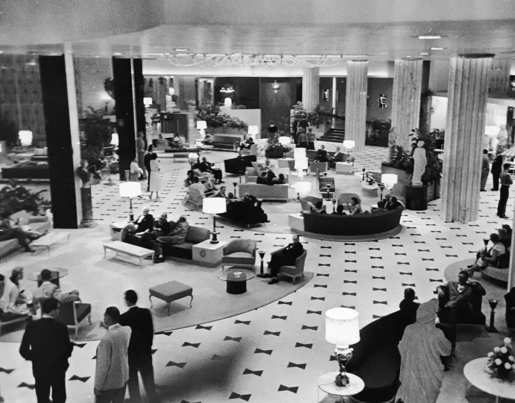 Fotografia histórica em preto e branco do amplo lobby do Fontainebleau Miami Beach, com hóspedes e mobiliário da época (1956)