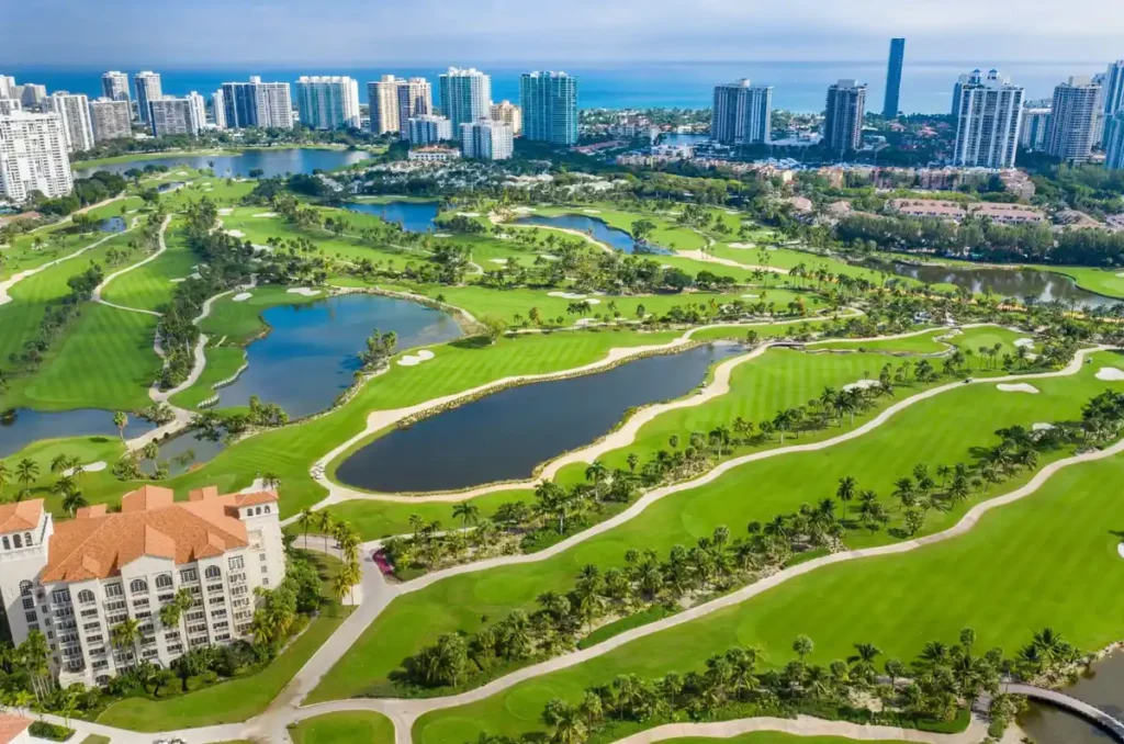 Campo de golfe do JW Marriott Miami Turnberry Resort & Spa, com lagos, palmeiras e o skyline da região de Miami ao fundo.