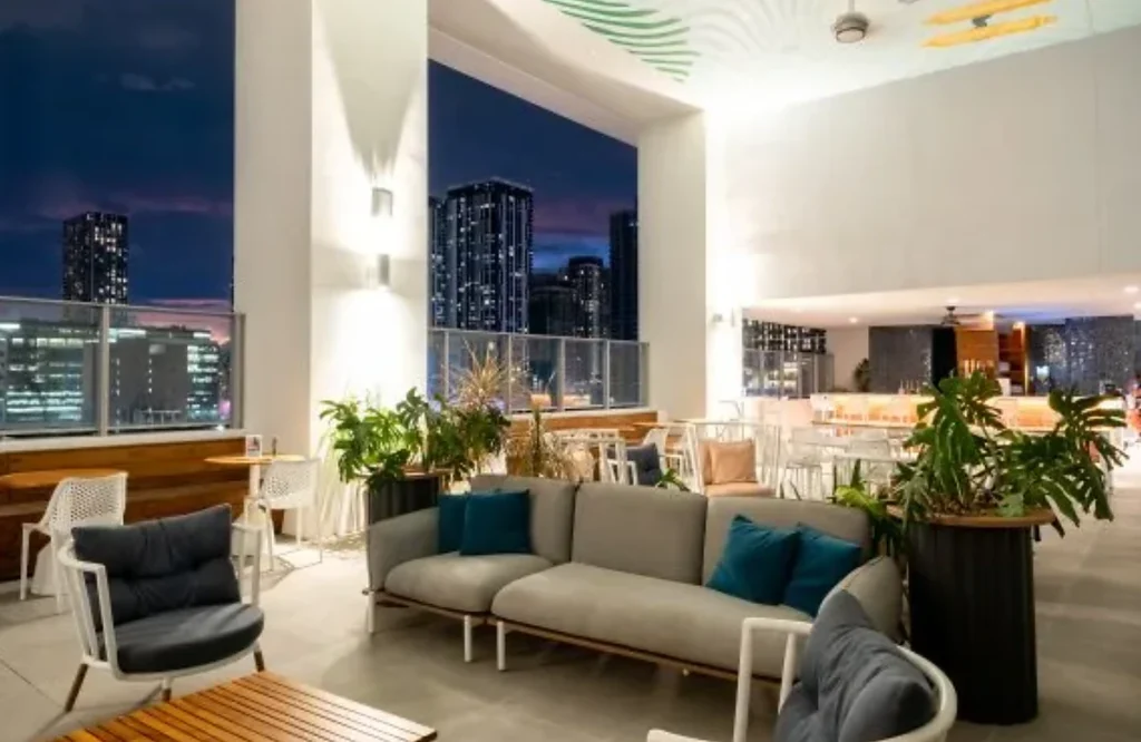 Rooftop do YOTEL Miami Downtown com sofás e vista noturna de Miami
