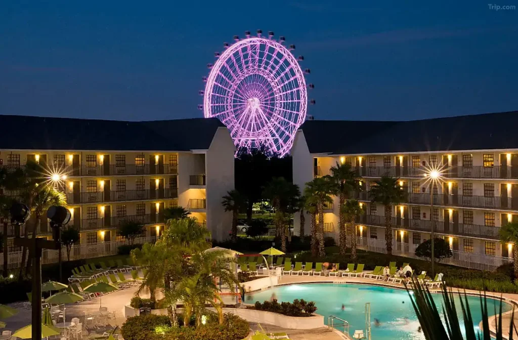 Vista noturna da piscina do Avanti International Resort, com a roda-gigante do ICON Park iluminada ao fundo, em Orlando, Flórida.