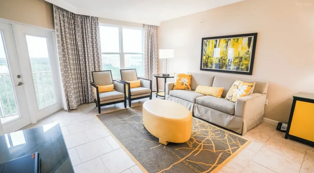 Área de estar do Vacation Village at Parkway com sofá, poltronas e acesso à varanda da acomodação.